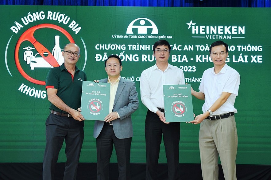Đại diện hãng bia Heineken (bìa trái) và đại diện Ủy ban ATGT Quốc gia (bìa phải) trao bộ quy tắc ATGT cho các đơn vị tham gia. Ảnh Đỗ Doãn